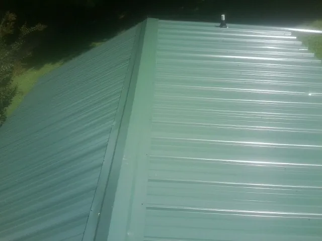 New green metal panels meeting at the ridge of a roof — Flat Roof Repair work by our crew in Fort Pierre