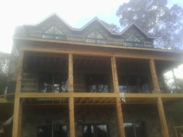 Dormers and porch framing on a large log home under construction — Roof Coating work by our crew in Fort Pierre