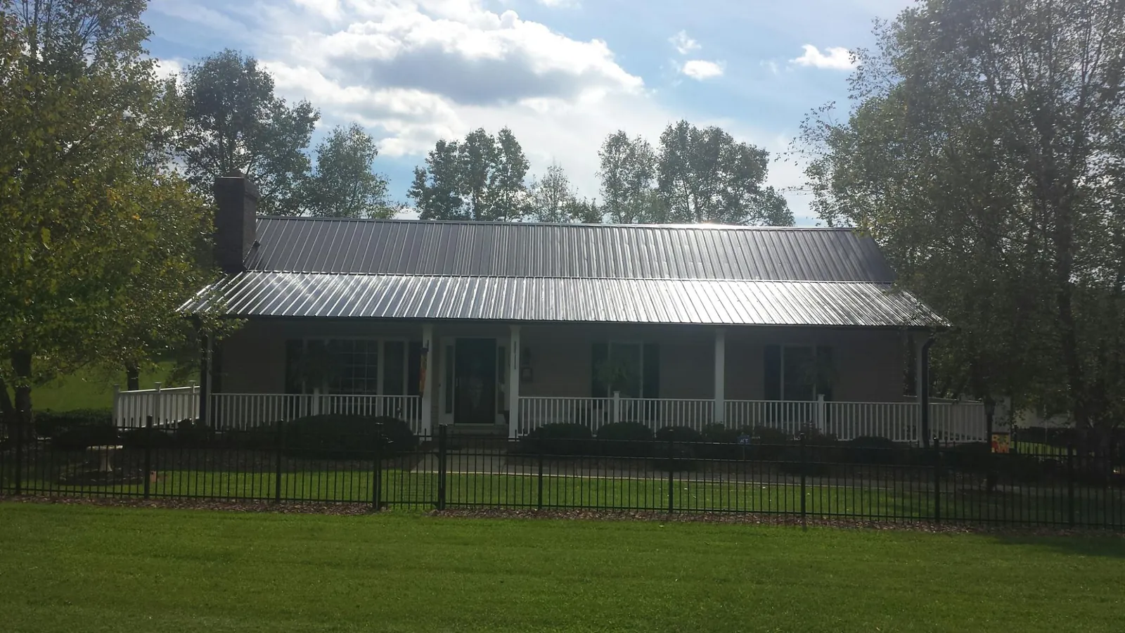 Gray metal roof on a brick ranch with a full width front porch — Gutter Guard Installation work by our crew in Fort Pierre