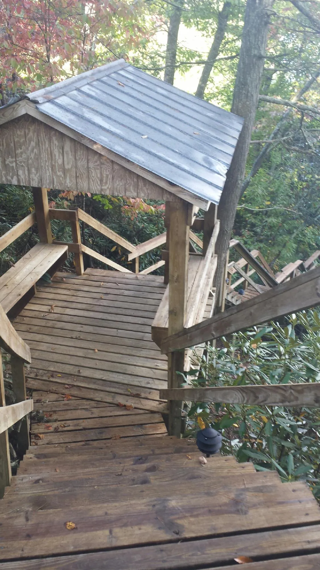 Metal roofed shelter over wooden steps on a wooded walkway — Skylight Repair & Installation work by our crew in Fort Pierre