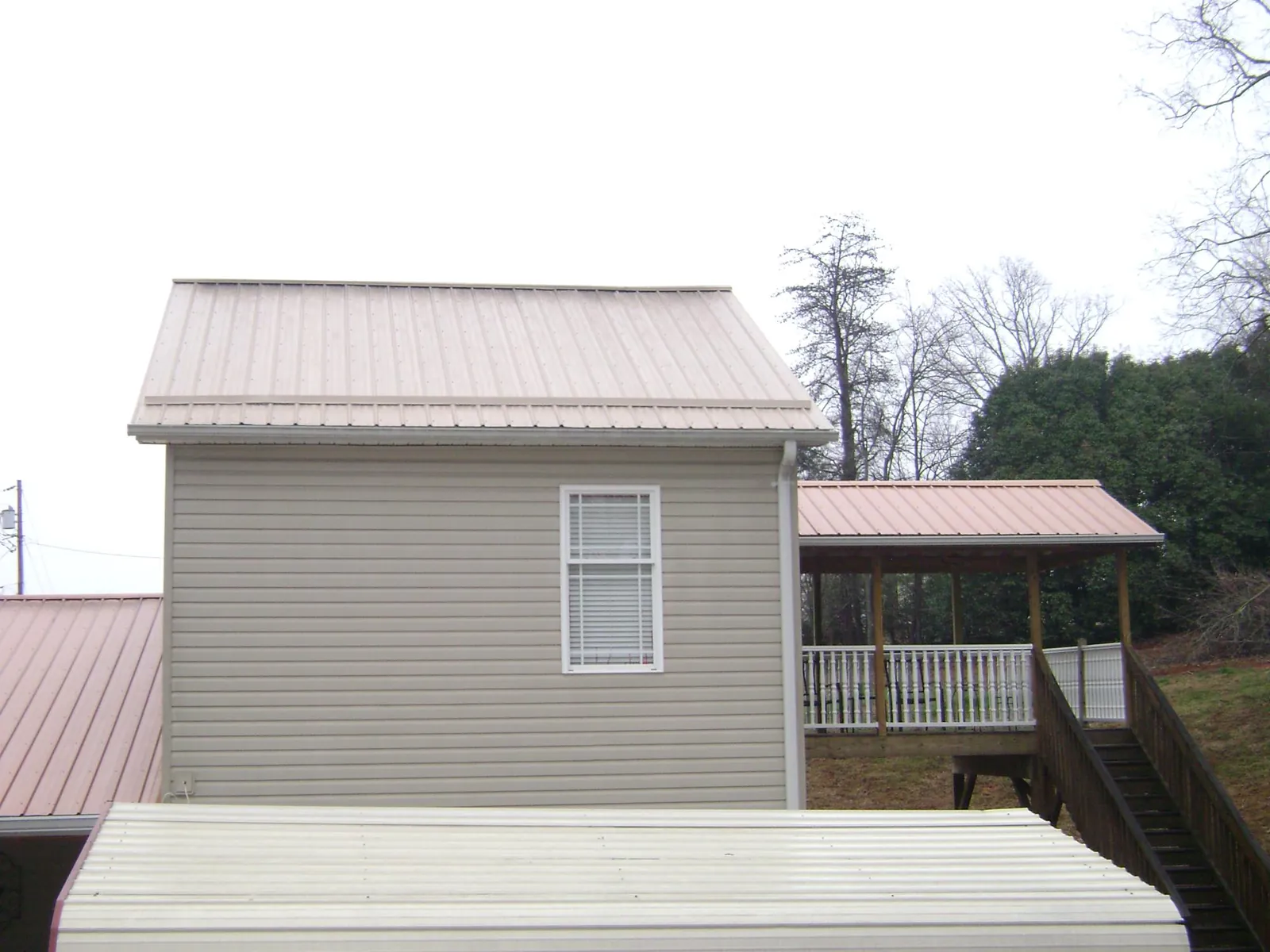 Tan metal roofs on a two story addition and attached porch, from a Roof Replacement job in Fort Pierre