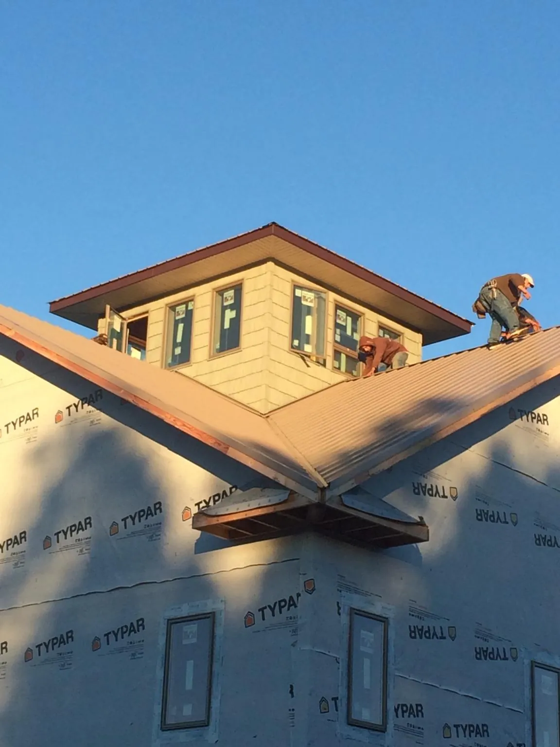 Roofers working around a rooftop cupola on a new metal roof at sunset — Roof Waterproofing in Fort Pierre by Roofing Brothers